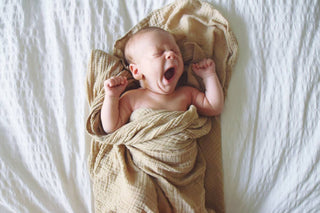   Um bebê de 3 semanas se espreguiça e boceja