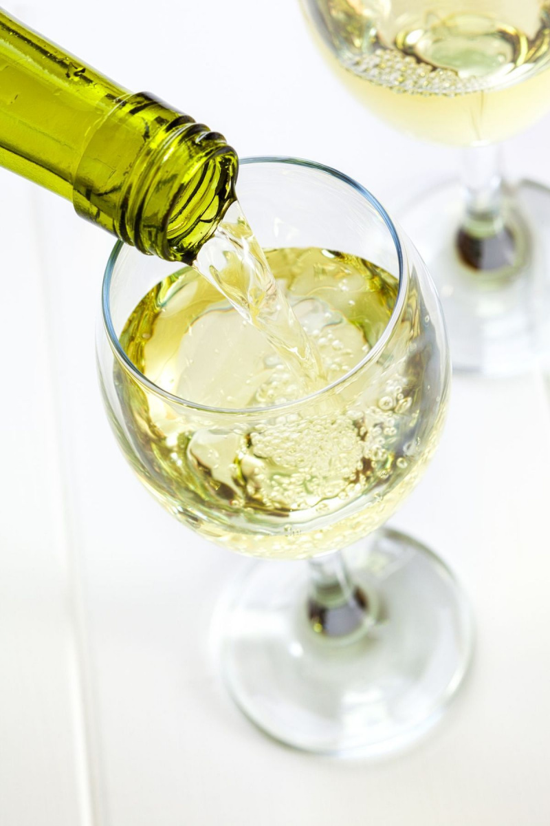 glas witte wijn wordt ingeschonken