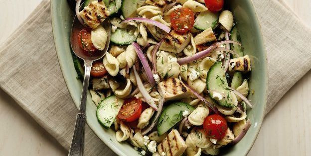 preparação de refeição de macarrão com salada grega