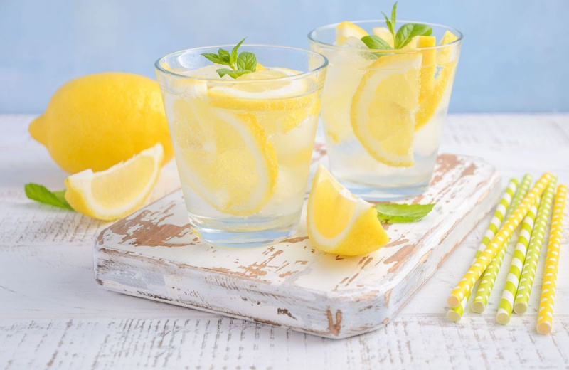 Bebida refrescante fria de verão com limão e hortelã em fundo de madeira.