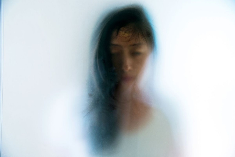 وجه امرأة يحدق من خلال زجاج بلوري