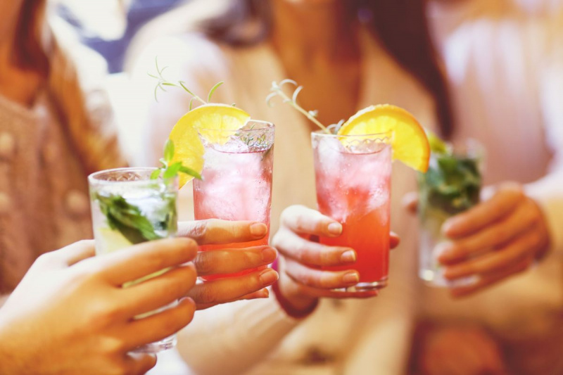 Unga män och kvinnor dricker cocktail på fest