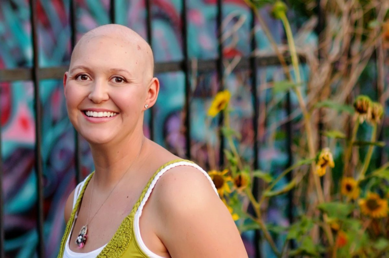 भित्तिचित्र दीवार के सामने कैंसर से पीड़ित गंजी महिला