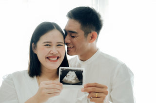   Um casal mostra uma foto de ultrassom de bebê para anunciar uma gravidez
