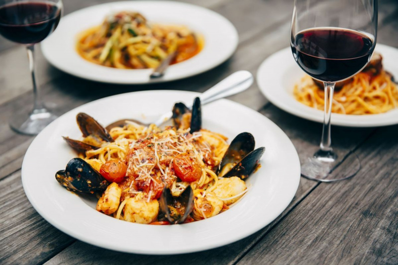 वाइन ग्लास के साथ समुद्री भोजन और पास्ता की प्लेट