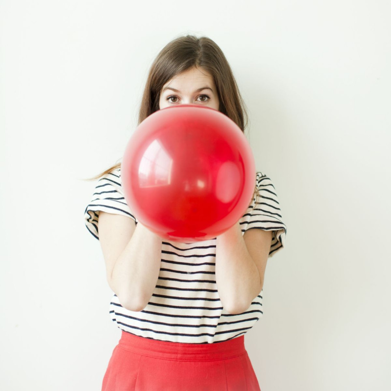 Foto d’estudi d’una dona jove que bufava globus